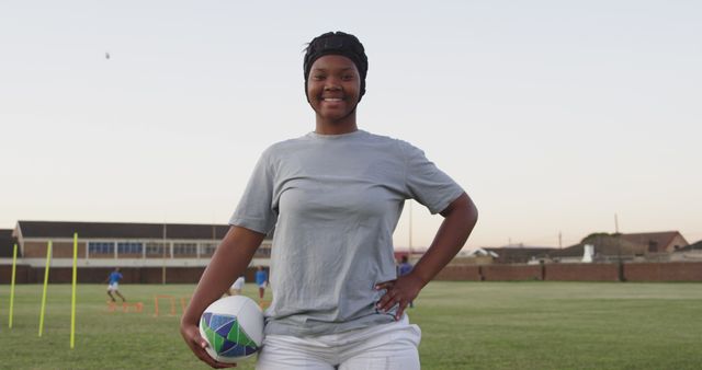 Confident Female Rugby Player Holding Ball on Field at Dusk - Download Free Stock Images Pikwizard.com