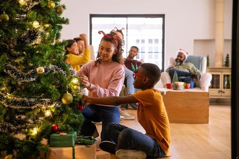 Joyful Children Decorating Christmas Tree with Family Smiling