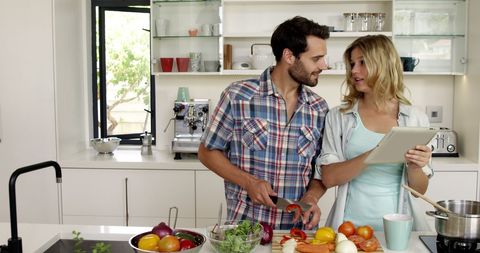Couple embracing modern cooking with technology in kitchen