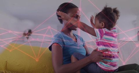 Black mother holding young daughter on couch bonding with pink digital network overlay
