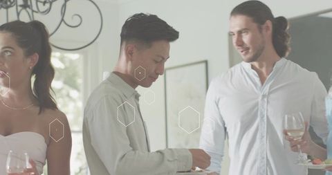 Asian man handling plate at casual home gathering with friends and wine glasses