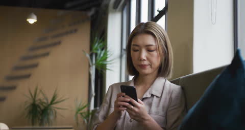 Businesswoman Using Smartphone in Relaxed Office Setting