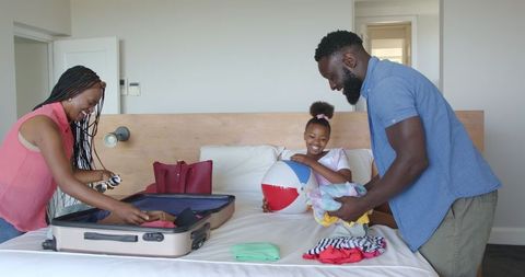 Family packing suitcase for vacation at home