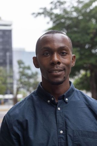 Confident young man standing on city street wearing navy button-down shirt
