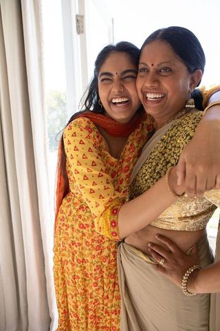 Indian mother daughter hugging in sunlight living room