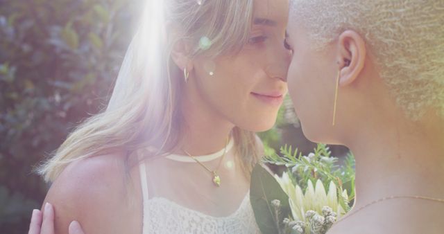 Women embracing and sharing a tender, romantic moment outdoors under sunlight, with greenery and flowers in the background. Ideal for concepts of LGBTQ+ love, romance, intimate weddings, tenderness, and equality. Could be used in advertisements, greeting cards, and promotional materials celebrating love and diversity.