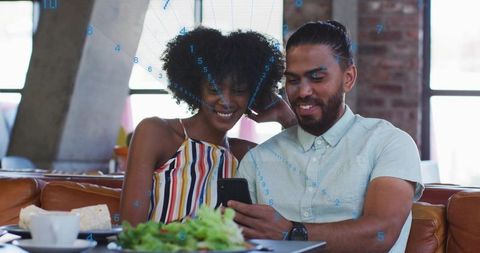 Young couple sharing smartphone while enjoying casual lunch on leather banquette in urban cafe