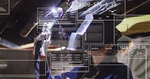 Automotive technician welding undercarriage with augmented reality HUD overlays in workshop