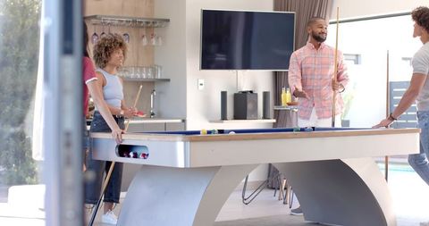 Friends playing pool in modern home lounge during casual social gathering with billiards