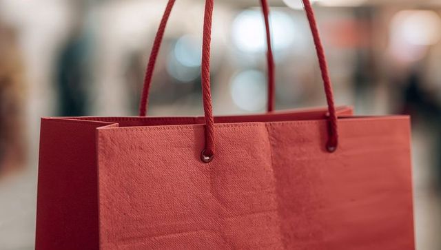 Hanging Red Shopping Bag Featuring Rope Handles and Matte Textured Surface in Store
