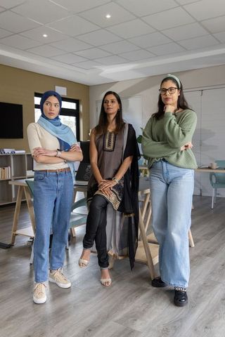 Diverse female professionals standing in modern office collaborating on creative project