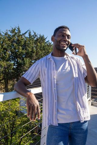 Smiling Man Enjoying Urban Rooftop View While On Phone Call