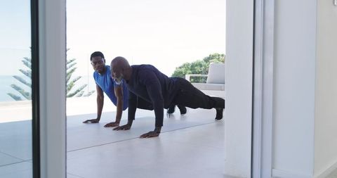 African american men training with push-ups on modern seaside terrace