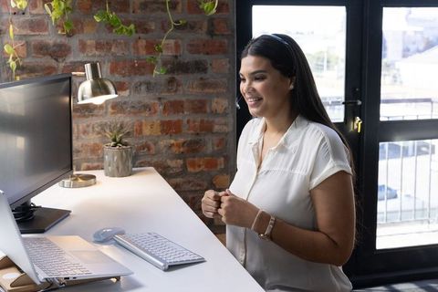 Woman working remotely at modern brick office with standing desk