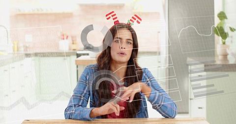 Young woman presenting augmented reality data dashboard at kitchen table, gesturing