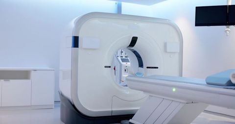 Modern ct scanner in minimalist clinical imaging suite with patient table and monitors