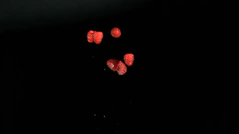 Falling Ripe Raspberries Against Black Background in Slow Motion