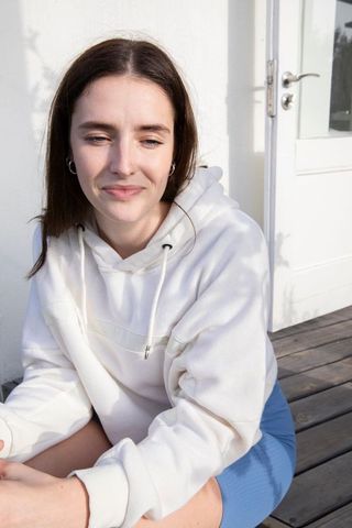 Relaxed young woman outdoors in casual white hoodie