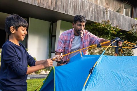 Father and son enjoying camping in backyard