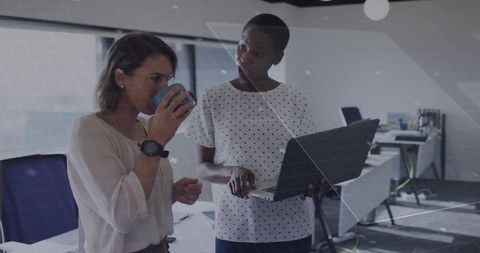 Professional Women Collaborating on Laptop Project in Modern Office