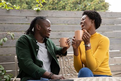 Smiling Couple Enjoying Coffee Outdoors on Wooden Patio