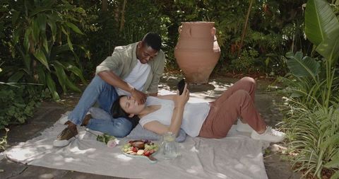 Interracial Couple Lounging on Picnic Blanket in Garden
