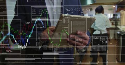 Asian analyst reviewing finance charts on tablet while interacting with trading dashboards