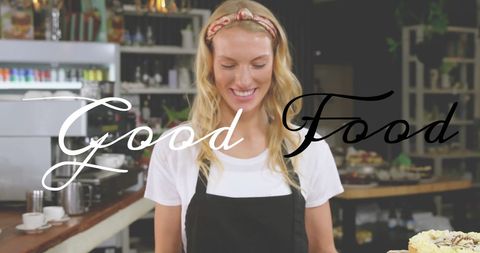 Smiling woman in apron with good food text in cafe