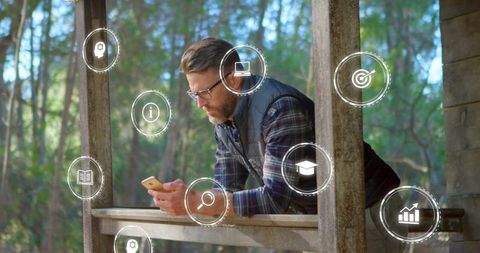 Midlife man leaning on rustic porch railing using smartphone with floating digital ui icons