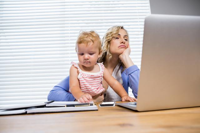 Stressed Mother with Baby Girl Using Laptop at Home - Download Free Stock Photos Pikwizard.com