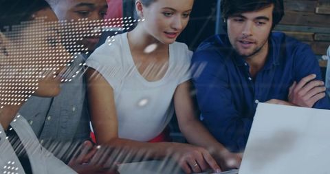 Young professionals collaborating with woman pointing at laptop screen in coworking space