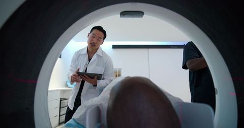 Doctor preparing african american patient for ct scan in modern radiology suite