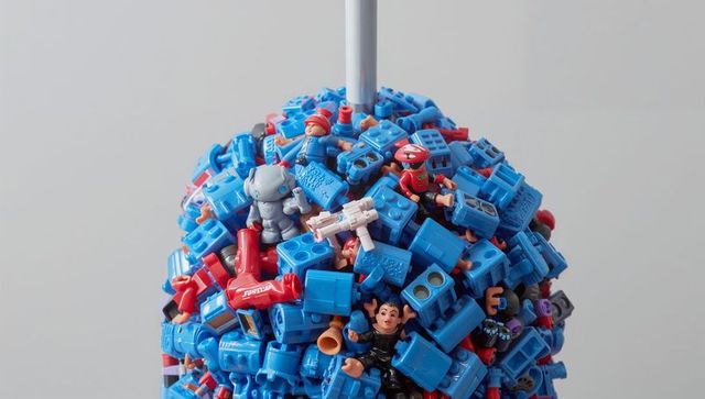 Blue modular toy sculpture with mini figures, red accents and silver robot on pole