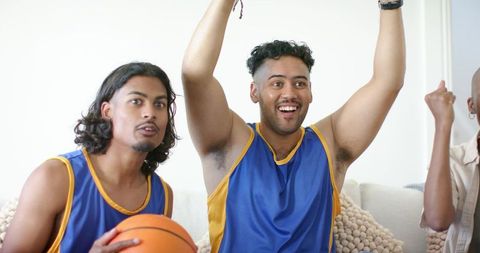 African american friends cheering and celebrating while watching basketball game on couch