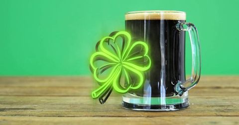 Dark stout mug with neon shamrock glow on rustic wood for st patrick promotion