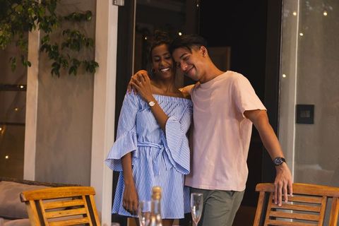 Evening cozy patio romance african american woman and asian man embracing by dinner table