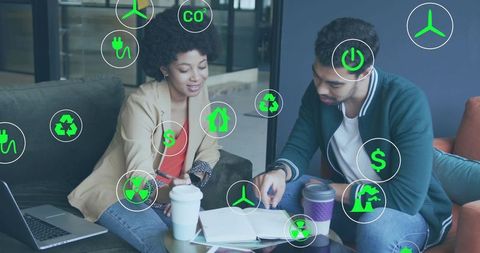Coworkers brainstorming sustainable energy solutions on sofa with green technology icons