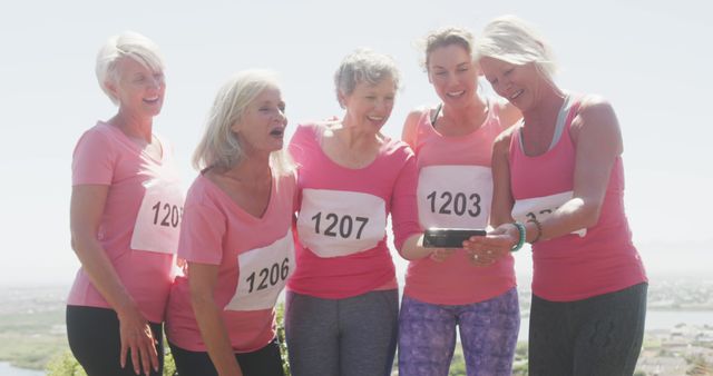 Happy diverse women wearing pinkt t-shirts with numbers taking selfie and smiling. Sport, support, friendship, healthy and active lifestyle.