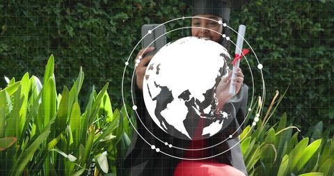 Graduate taking selfie holding diploma with globe overlay in lush garden