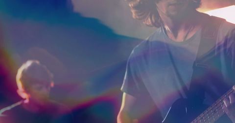 Guitarist performing on stage with vibrant light effects