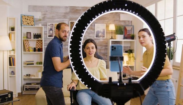 Creators filming livestream with ring light and smartphone tripod in home studio