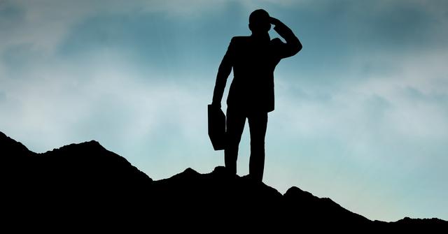 Digital composite of Silhouette businessman standing on mountain against sky