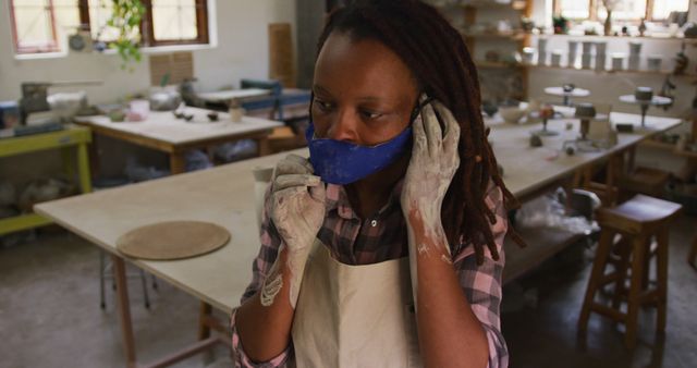 Portrait of female african american potter with dirty hands in clay at pottery studio. hygiene and social distancing in the pottery studio during coronavirus covid 19 pandemic.