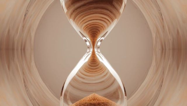 Elegant metallic hourglass with flowing sand and beige swirl backdrop