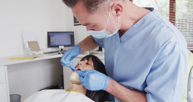Caucasian male dentist with face mask examining teeth of female patient at modern dental clinic. healthcare and dentistry business during covid 19 pandemic.