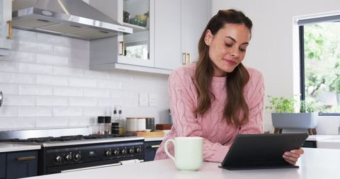 Woman Relaxing with Tablet in Cozy Modern Kitchen Interior
