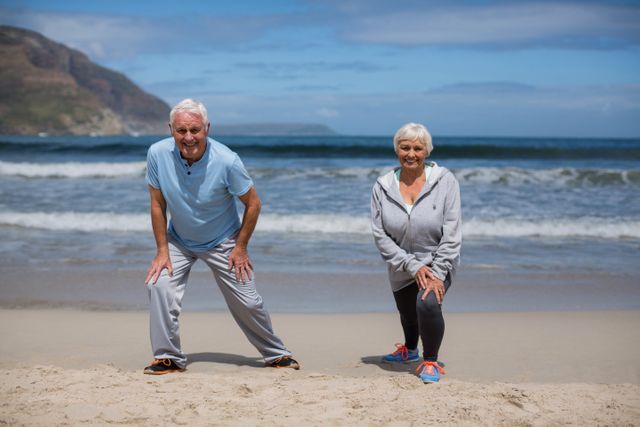 Senior couple doing stretching exercise on the beach - Download Free Stock Photos Pikwizard.com
