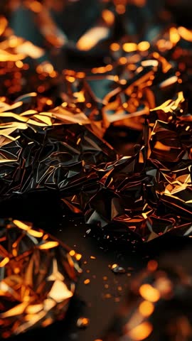 Panning revealing crumpled metallic foil with glowing amber reflections and droplets