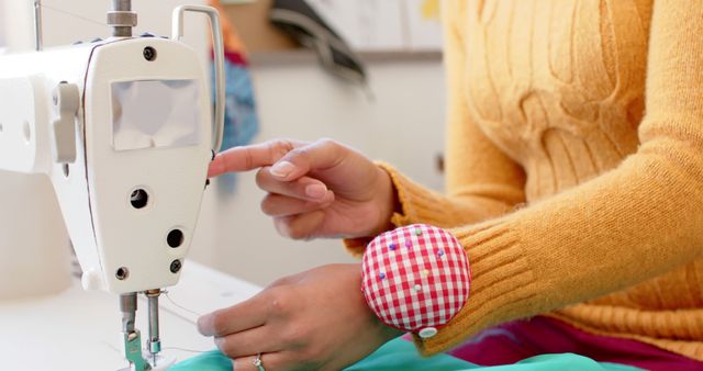 Close-up view of person sewing with sewing machine. Hands carefully guiding fabric while needle pierces material. Ideal for topics related to fashion design, DIY crafts, textile work, tailoring, and handmade clothing.