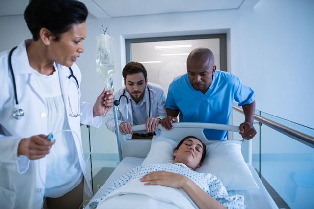 Medical professionals adjusting an IV drip for a patient lying in a hospital bed. Ideal for use in healthcare, medical care, hospital services, emergency treatment, and patient recovery contexts.